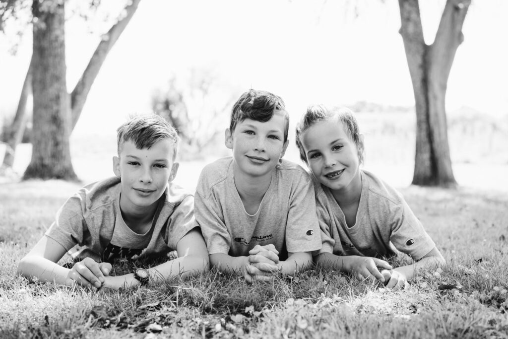 Three brothers lying on grass, black and white