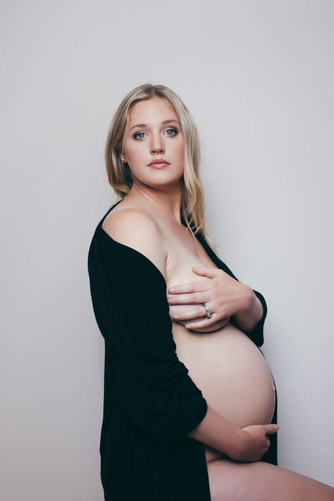 Expectant mother in a green dress, studio maternity portrait