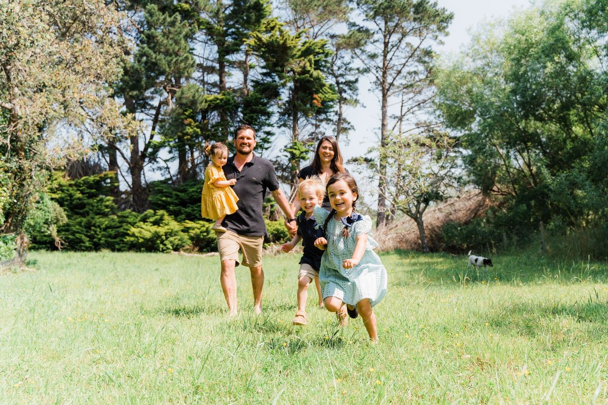 A family running towards the camera across a sunny lawn