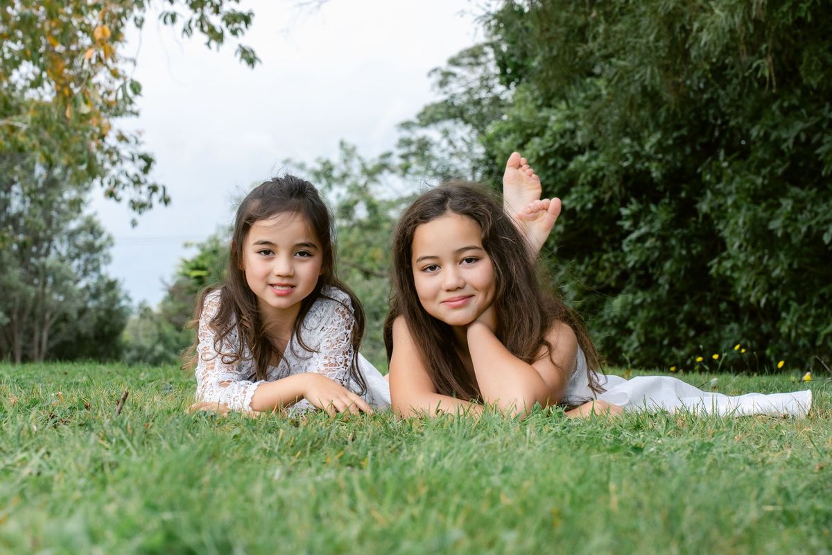 Two sisters lying on the grass, smiling