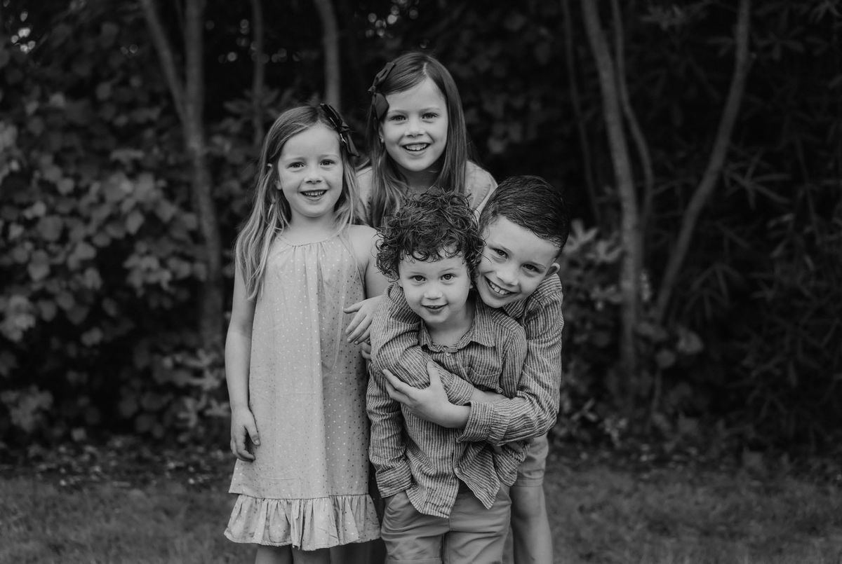 Three siblings huddled together laughing, black and white