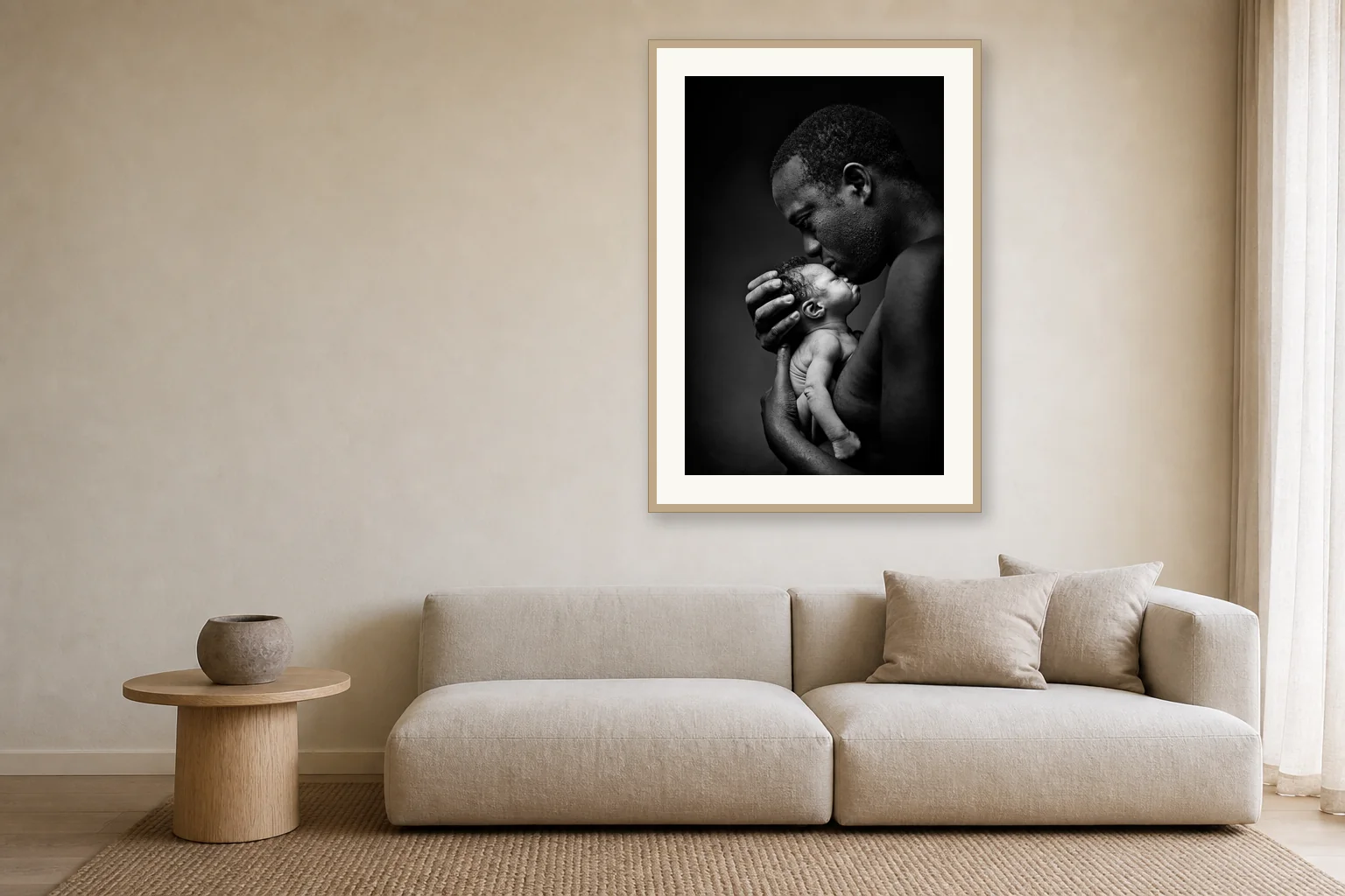 One large framed black and white portrait of a father kissing his newborn, hung above a linen sofa