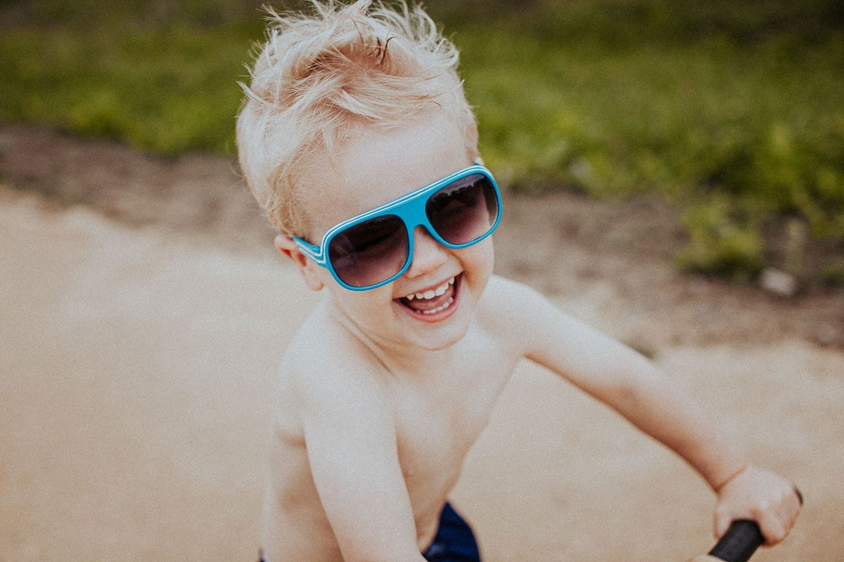 A laughing boy in blue sunglasses